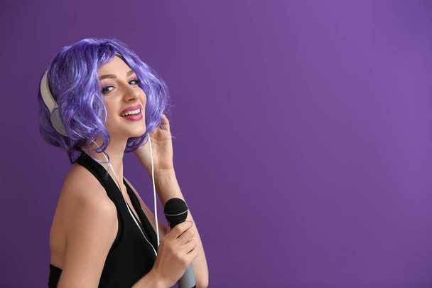 Όμορφη νεαρή γυναίκα με μικρόφωνο και ακουστικά για χρώμα φόντου - Φωτογραφία, εικόνα