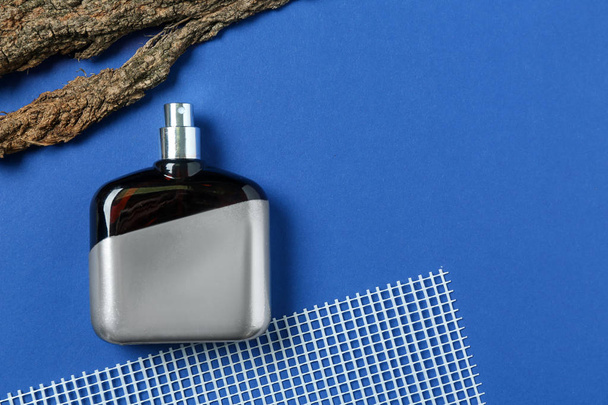 Fles parfum en boom schors op kleur achtergrond - Foto, afbeelding