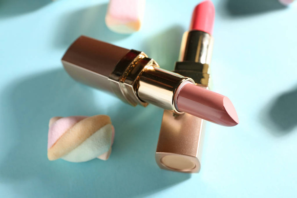 Lipsticks and sweet marshmallow on color background - Foto, afbeelding