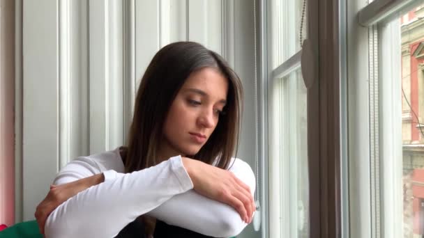 Szomorú sepressed fiatal nő ül egy ablak otthon a sírás - Felvétel, videó