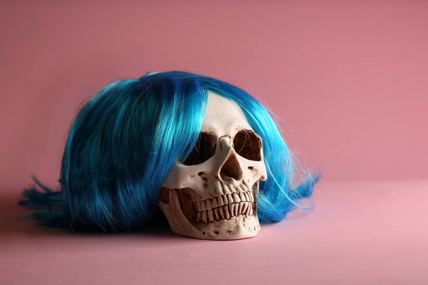 Human skull with wig on color background - Foto, imagen
