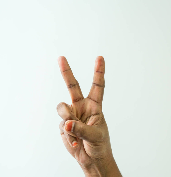Hands brown skin with fingers making victory or peace sign on white background - Foto, Bild