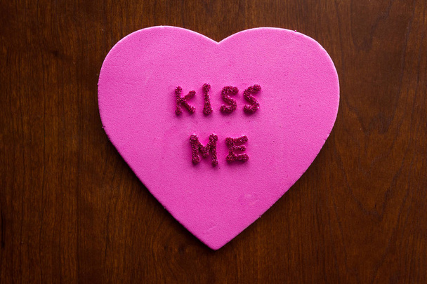 les mots m'embrassent en lettres scintillantes sur un coeur rose collé sur une armoire en bois
 - Photo, image