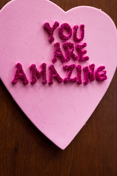 the words you are amazing in glitter letters on a pink heart stuck on a wooden cabinet - Foto, immagini