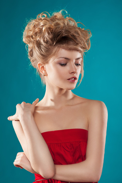 Hermosa modelo rubia con el pelo rizado mirando hacia abajo, las manos dobladas
 - Foto, Imagen