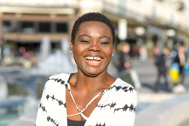 Happy temperamentní mladá Afričanka v postavení města v sunshine v ulici, směje se na kameru - Fotografie, Obrázek
