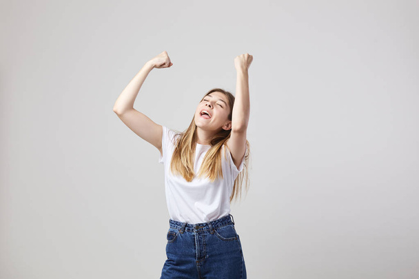 Cheerful and calm girl dressed in a white t-shirt and jeans has fun on a white background in the studio - Foto, afbeelding