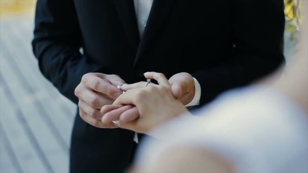 A vőlegény hozza a wedding ring ujját a menyasszony, és megcsókolja a kezét. A menyasszony és a vőlegény cseréje esküvői Jegygyűrűk. - Felvétel, videó