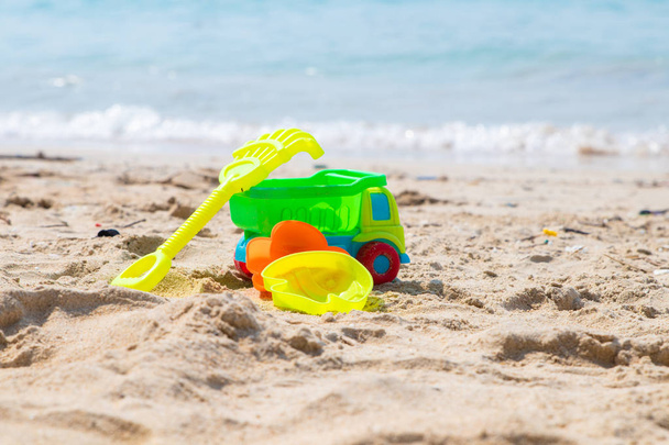 Childrens beach toys - buckets, spade, machine, car and shovel on sand on a sunny day - Photo, Image