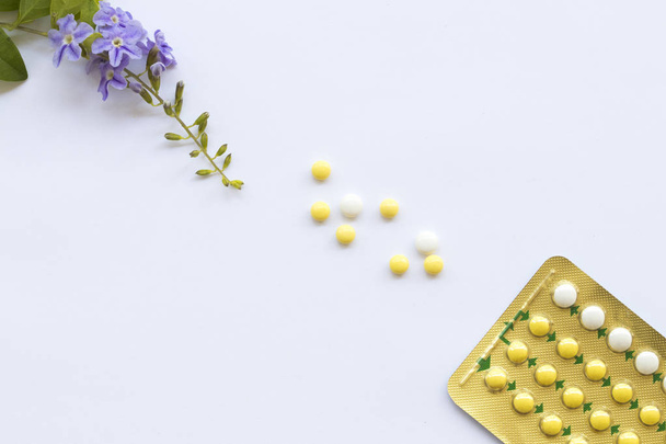 geboortebeperking pillen anticonceptiva vrouw voor niet wilt hebben baby met paarse bloemen decoratie plat lag stijl op witte achtergrond  - Foto, afbeelding