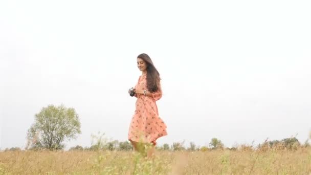 Beautiful girl takes pictures of nature. Field with green grass. Slow motion. Wind develops hair - Footage, Video