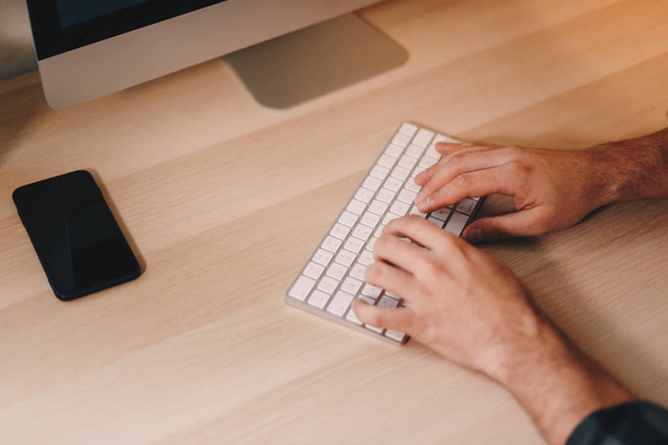 Üstten görünüm ahşap çalışma masası üzerinde ayarla bir kablosuz klavye yazarak adamın parmak kadar yakın. - Fotoğraf, Görsel