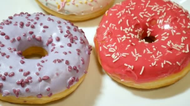 Three donuts with colorful sprinkles on white plate. Unhealthy sugar abuse addiction concept, HD - Footage, Video