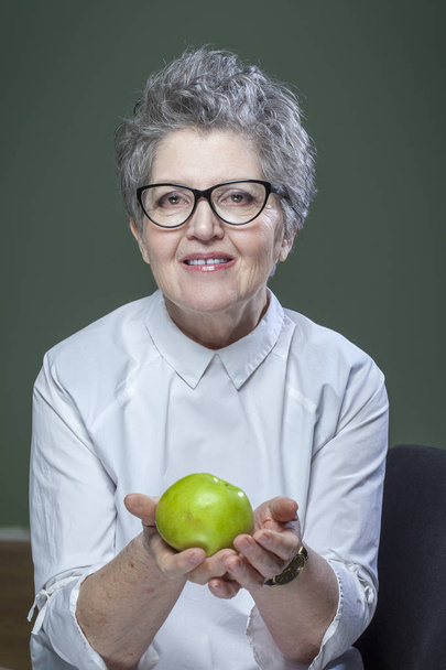 yaş, sağlıklı beslenme, gıda, beslenme ve insan kavramı - yakın, mutlu gülümseyen kadın kıdemli yeşil elma ile - Fotoğraf, Görsel