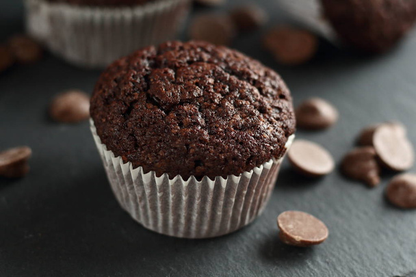 Chocolate homemade cupcakes muffins on a black background with chocolate drops in the background. Bakery style. Dark food photo - Photo, Image