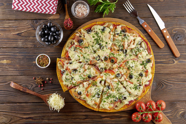 Fresh pizza on the wooden table with ingredients around. Flat lay with top view - Photo, Image
