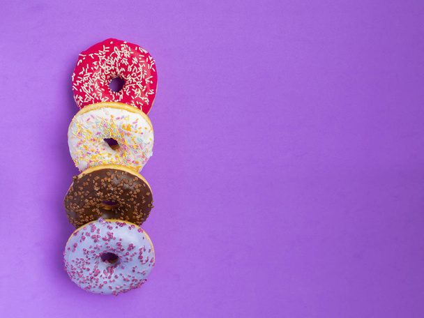 vier verschiedene Donuts liegen auf lila Hintergrund - Foto, Bild