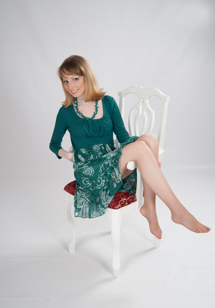 l woman in a green dress sitting on a chair - Фото, изображение