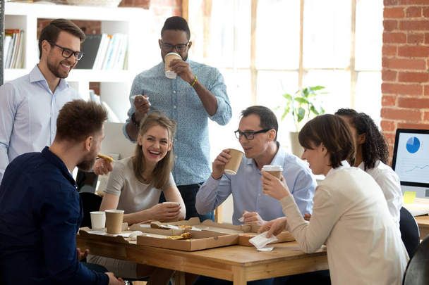 Мультиэтнические сотрудники группы пользуются еду на вынос дружественный разговор в офисе
 - Фото, изображение