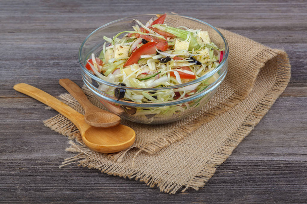 Fresh vegetables and vegetable salad in dishes on wooden background. - Fotografie, Obrázek