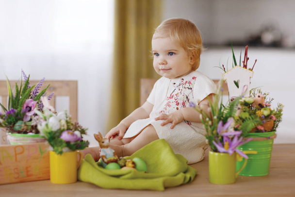 Счастливый ребенок сидит за столом и держит пасхальное яйцо
 - Фото, изображение