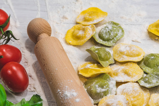 Domowe pierożki włoski świeży makaron na biały stół z drewna z mąki, bazylia, pomidory, tło - Zdjęcie, obraz