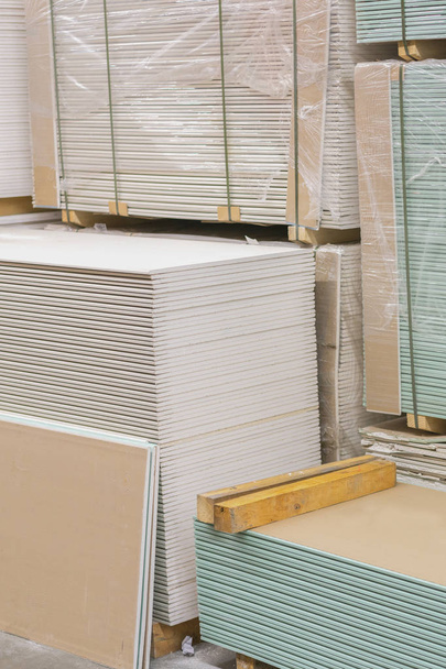 Gypsum plasterboard in the pack. The stack of gypsum board preparing for construction. Pallet with plasterboard in the building store. Construction Materials. Drywall warehouse. vertical photo - Photo, Image