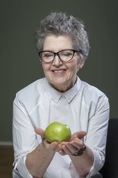 возраст, здоровое питание, еда, диета и концепция людей - крупным планом счастливая улыбающаяся пожилая женщина с зеленым яблоком
 - Фото, изображение