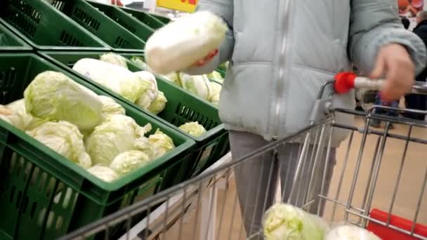 woman takes Chinese cabbage away out of cart puts into box - Materiał filmowy, wideo
