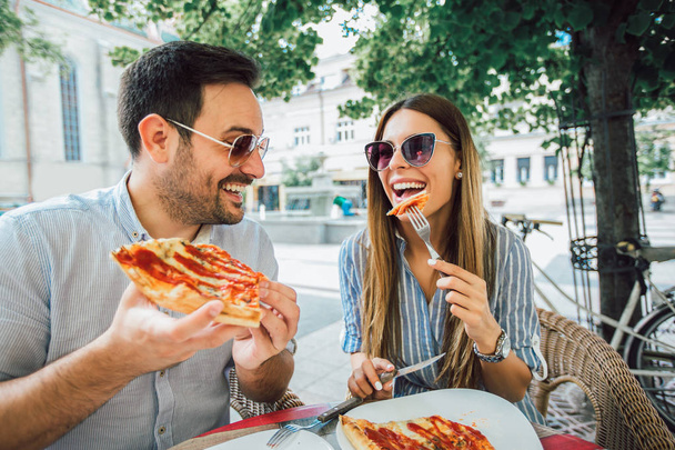 Pareja comiendo pizza snack al aire libre.Están compartiendo pizza y comiendo
. - Foto, Imagen