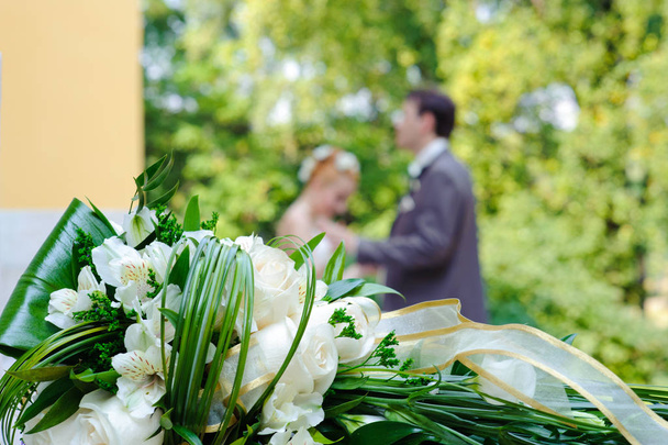 Beautiful wedding bouquet and newlyweds in the background. - Photo, Image