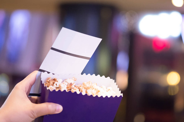 Kinokarten und Eimer Popcorn in der Hand, Freizeitkonzept - Foto, Bild