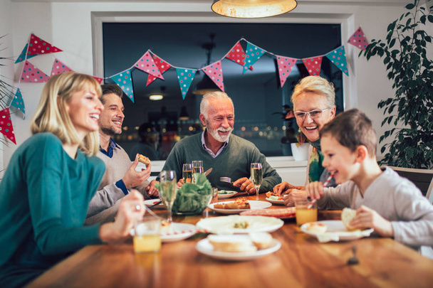Famiglia multi generazione che si gode il pasto a tavola a casa
  - Foto, immagini