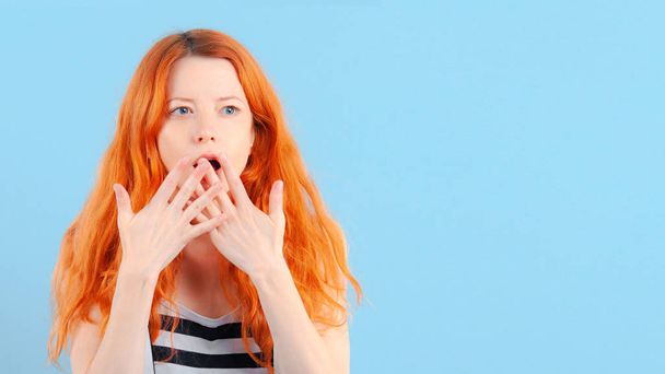 Redhead girl covers her mouth with her hand. Surprise and shock. Emotions and lifestyle - Foto, Imagen