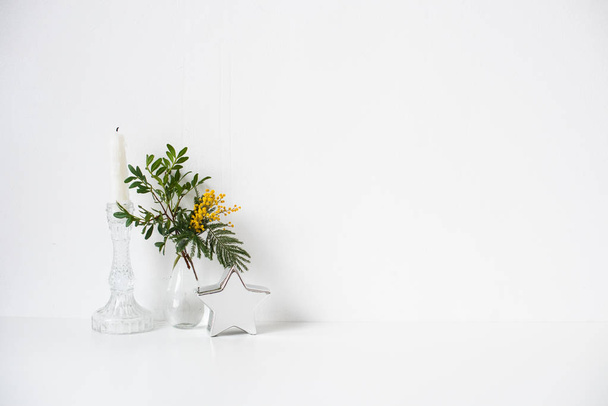 Small bouquet with green leaves and mimosa flowers and empty white wall - Photo, Image