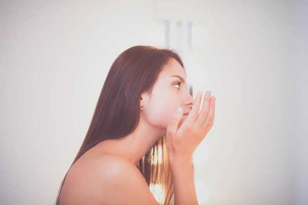 Attractive young woman applying cream on her Face - Valokuva, kuva