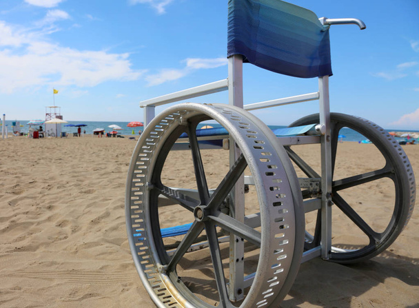 ingeniosa silla de ruedas con ruedas modificadas para moverse incluso en la playa de arena del pueblo turístico en el verano
 - Foto, Imagen