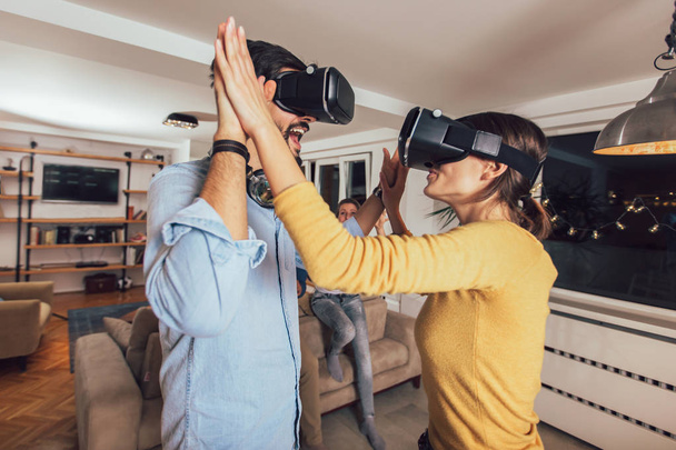 Genç çift sanal gerçeklik kulaklık gözlük - mutlu insanlar yeni eğilimleri teknoloji ile oyun oynama ile eğleniyor  - Fotoğraf, Görsel