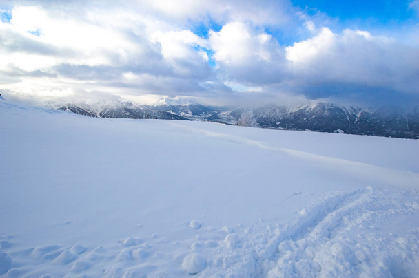 sommet d'une colline enneigée avec montagnes lointaines et ciel nuageux
 - Photo, image
