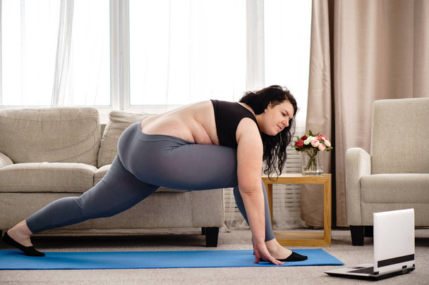 overweight woman stretching during home training - Foto, imagen