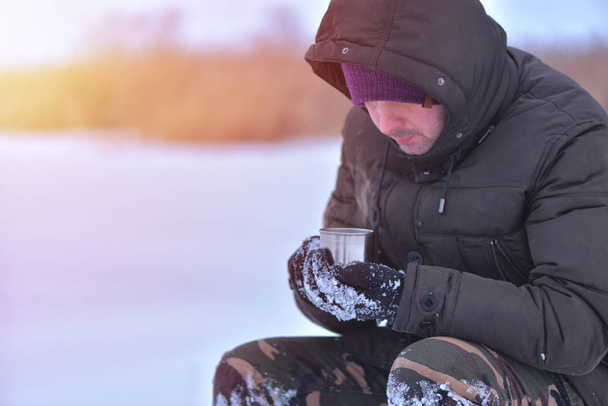 Vista lateral de la mano masculina en guantes sosteniendo taza con té o café caliente. Descanso. Concepto de invierno
 - Foto, imagen