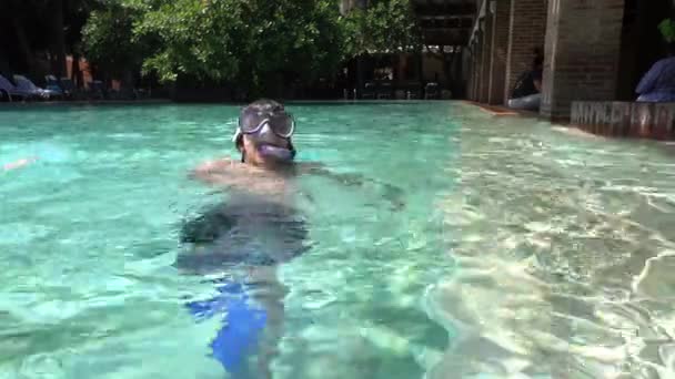 Teenager wearing mask swimming in the pool. Happy holiday concept. Cute happy little boy swimming and snorking in the sea ocean in crystal blue water - Metraje, vídeo