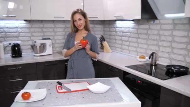 A woman in the modern kitchen picks up pepper, puts it to the heart and opens the vegetable. Smile gives way to rust. Symbol of a broken heart. 4K Slow Mo - Footage, Video