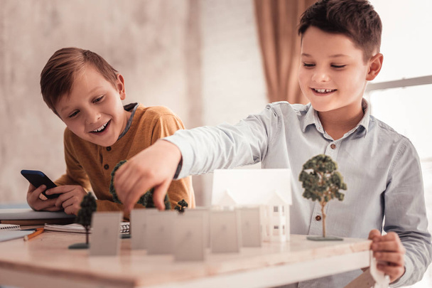 Two curious schoolboys building model of detached house - 写真・画像