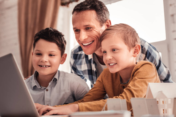 Smiling father feeling happy showing his children educational cartoon - Foto, imagen