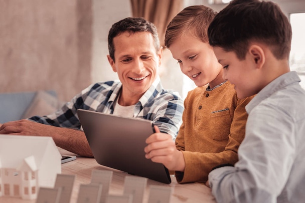 Two cute sons showing their photos to foster father on tablet - Fotoğraf, Görsel