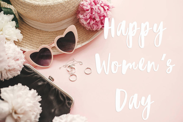 Hyvää naistenpäivää teksti merkki tyylikäs tyttömäinen vaaleanpunainen retro aurinkolasit, pioneja, koruja, hattu, kukkaro pastelli vaaleanpunainen paperi
 - Valokuva, kuva
