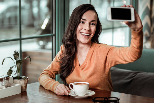 Pleased girl going to drink tasty coffee - Foto, Imagen