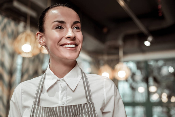 Dreamy waitress expressing positivity during her workday - Fotoğraf, Görsel