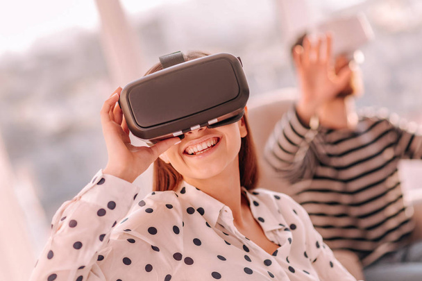 Smiling woman testing virtual reality device with friend - 写真・画像